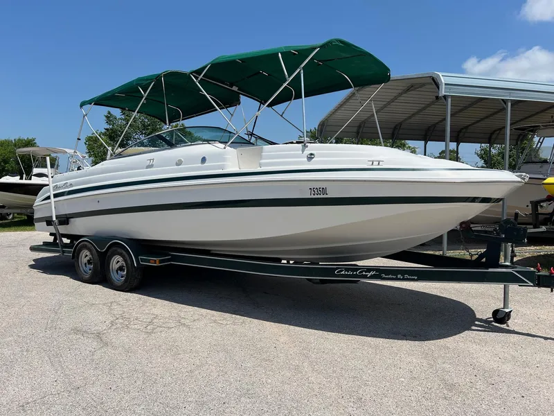 Slide: The Image of 2000 Chris-Craft 260DB boat with green canopy on a trailer, parked outdoors. - 3