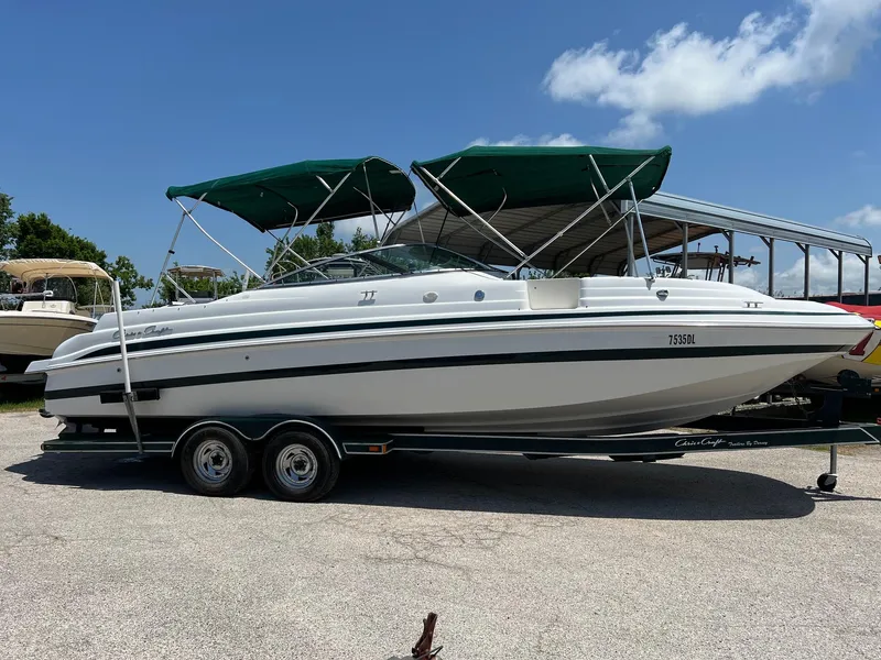 Slide: The Image of 2000 Chris-Craft 260DB boat on trailer with green canopy, parked outdoors. - 4