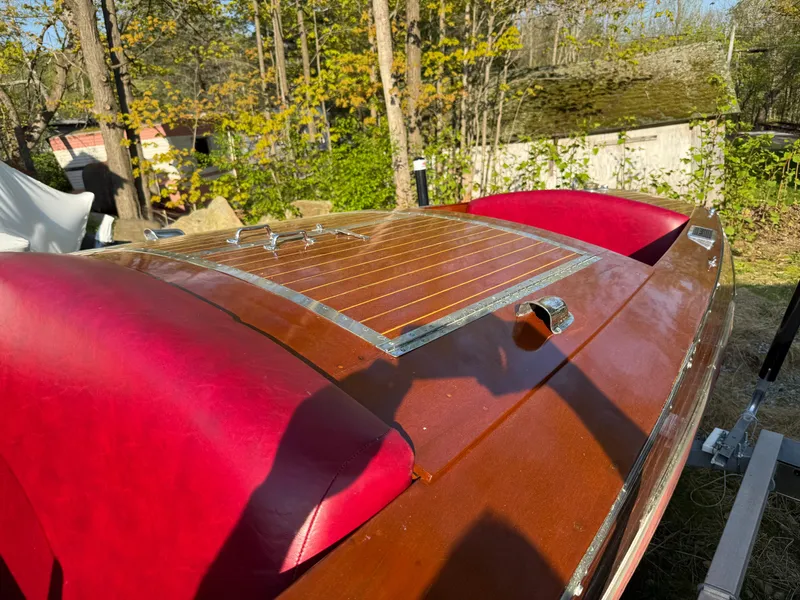 Slide: The Image of 1932 Chris-Craft 301 boat with red seats and wooden deck, surrounded by trees. - 10