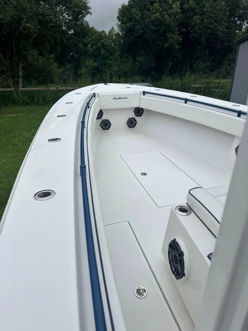 Slide: The Image of 2013 SeaHunter 35 Tournament boat, white deck, blue trim, outdoor setting, lush greenery background. - 18