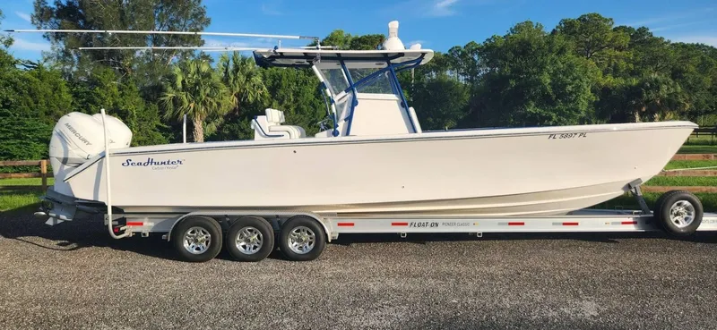 Slide: The Image of 2013 SeaHunter 35 Tournament boat on trailer, parked outdoors with trees in background. - 3