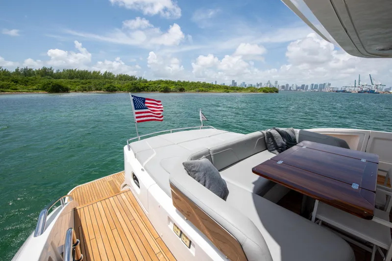 Slide: The Image of Luxurious 2021 Princess S66 yacht with American flag, cruising near lush coastline and city skyline. - 48