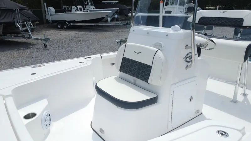 Slide: The Image of 2025 Tidewater 1910 Bay Max boat interior with seating and console, parked on gravel. - 27