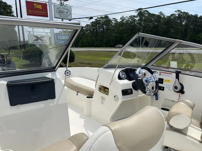 Slide: The Image of 2019 Stingray 191DC (OB) boat interior with beige seating and steering console. - 2