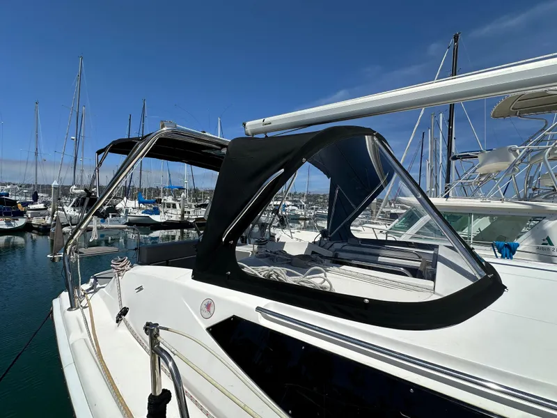 Slide: The Image of 2013 Hunter 33 sailboat with black canopy docked in marina under clear blue sky. - 7