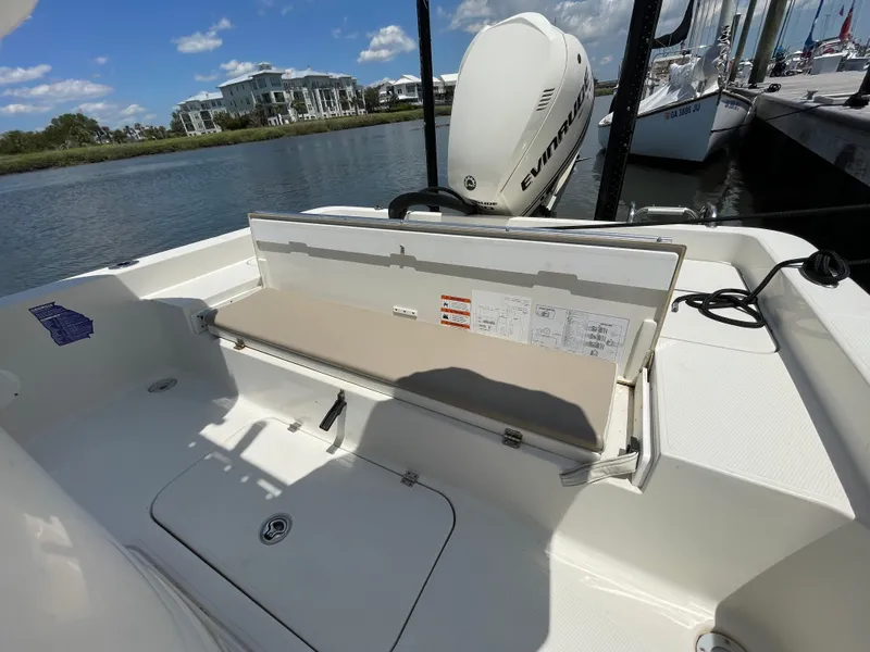 Slide: The Image of 2012 Ranger 2410 Bay Ranger boat with open storage compartment, docked by a scenic waterfront. - 17