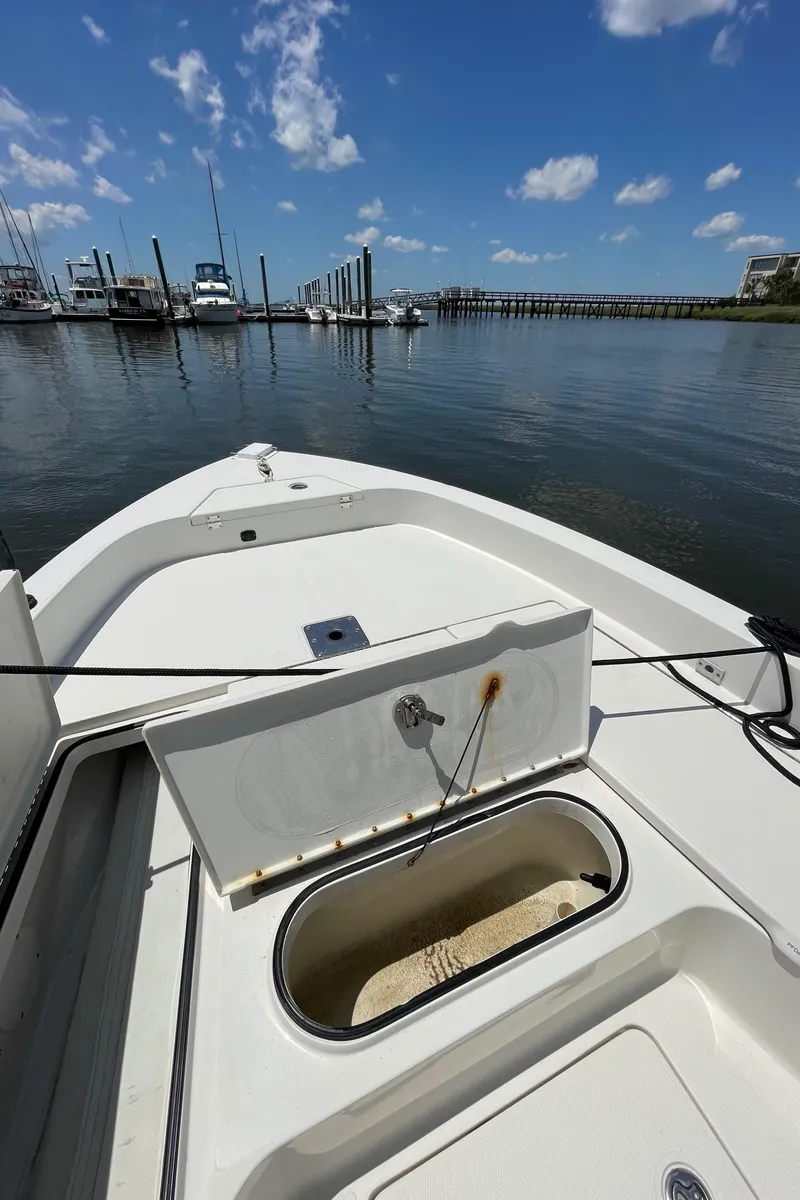 Slide: The Image of 2012 Ranger 2410 Bay Ranger boat docked, open storage compartment, clear sky, calm water. - 23