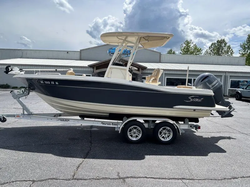 Slide: The Image of 2021 Scout 215 XSF boat on trailer, parked outdoors under cloudy sky. - 1