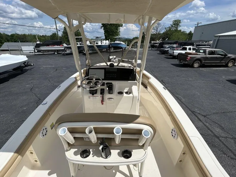 Slide: The Image of 2021 Scout 215 XSF boat interior with helm and rod holders, parked in a lot. - 11