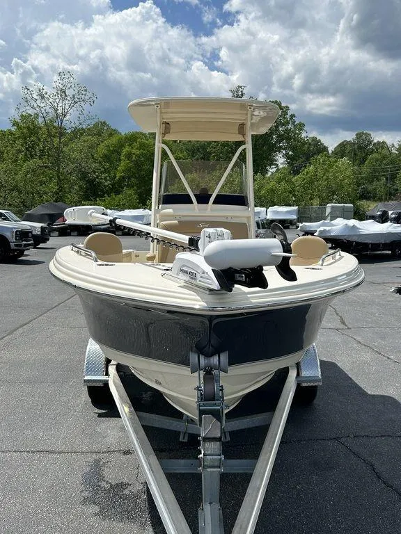 Slide: The Image of 2021 Scout 215 XSF boat on trailer, parked outdoors under cloudy sky. - 2