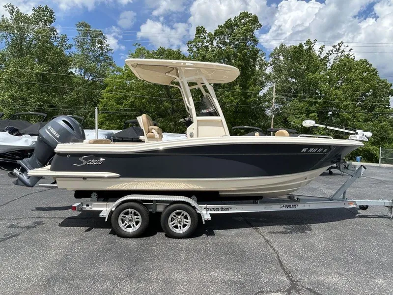 Slide: The Image of 2021 Scout 215 XSF boat on trailer, parked outdoors with trees in background. - 3