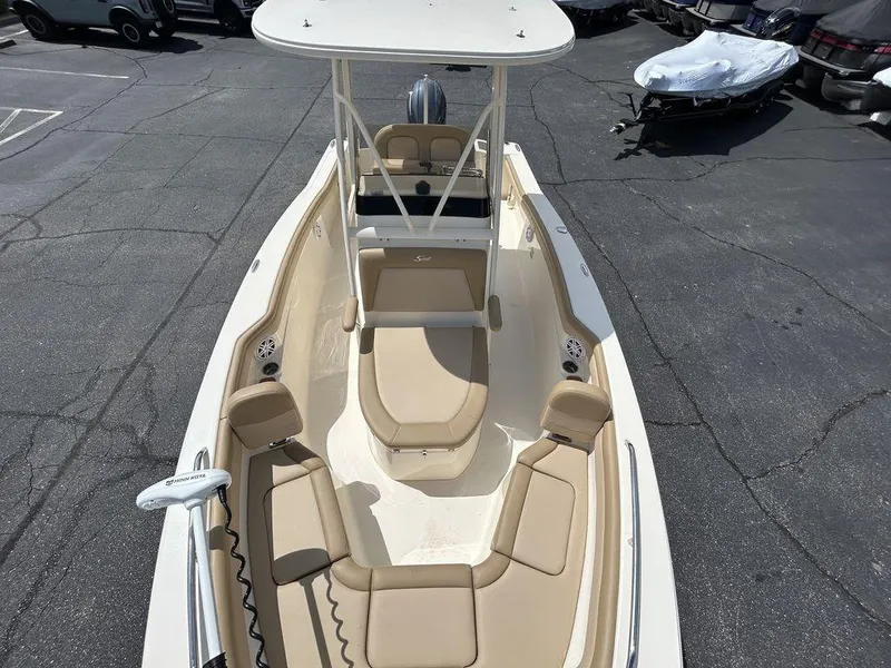 Slide: The Image of 2021 Scout 215 XSF boat with beige seating and T-top, parked on asphalt. - 5