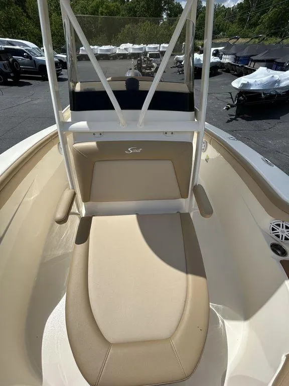 Slide: The Image of 2021 Scout 215 XSF boat with beige seating and console, parked outdoors. - 8