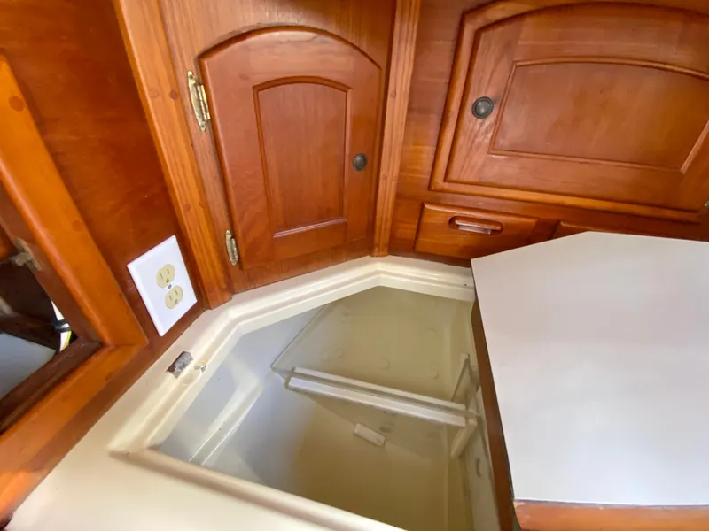 Slide: The Image of Interior of 1998 Pacific Seacraft 37, featuring wooden cabinetry and a built-in storage compartment. - 21