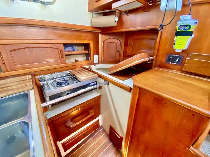 Slide: The Image of Interior of 1998 Pacific Seacraft 37 sailboat galley with wooden cabinetry and stove. - 22