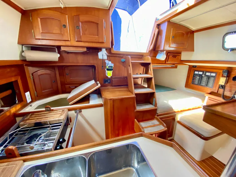 Slide: The Image of Interior of 1998 Pacific Seacraft 37 sailboat with wooden cabinetry and compact kitchen area. - 23