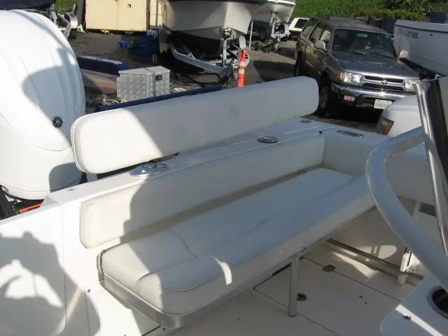 Slide: The Image of 2023 Edgewater 245CC boat with white cushioned seating in a marina setting. - 5