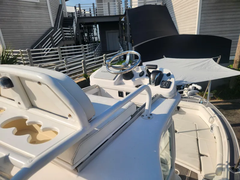 Slide: The Image of 2021 Everglades 243 Center Console boat with steering wheel and controls, docked near modern buildings. - 10