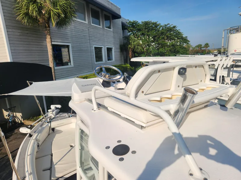 Slide: The Image of 2021 Everglades 243 Center Console boat docked near a building with palm trees. - 11