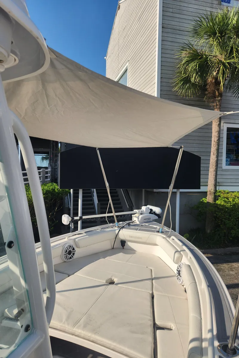 Slide: The Image of 2021 Everglades 243 Center Console boat with sunshade, docked near a building and palm tree. - 21