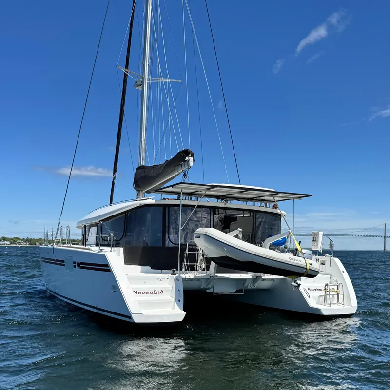 Slide: The Image of 2016 Lagoon 450S catamaran on water, featuring a dinghy and clear blue sky. - 2