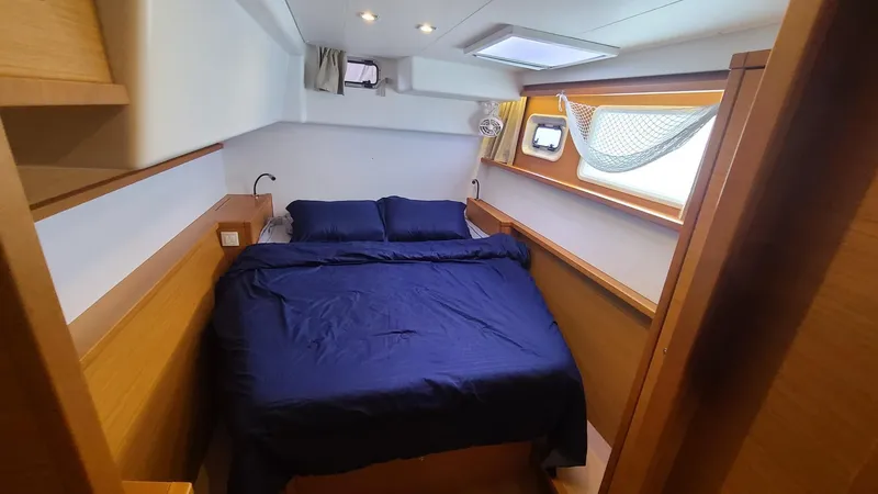 Slide: The Image of 2016 Lagoon 450S yacht cabin with blue bedding and wooden interior. - 21