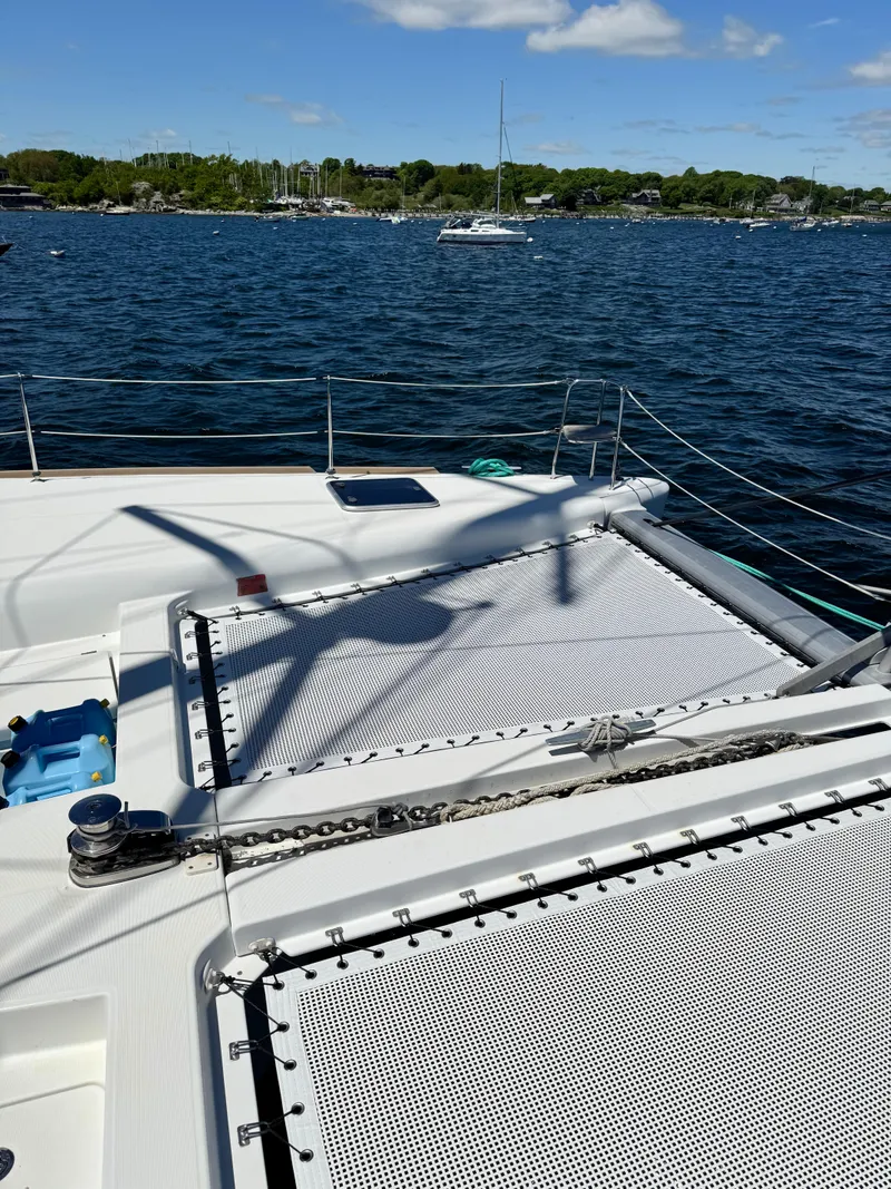 Slide: The Image of 2016 Lagoon 450S catamaran deck with netting, anchored in a scenic bay. - 44
