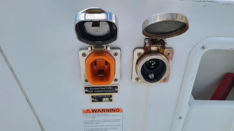 Slide: The Image of Electrical outlets on a 2016 Lagoon 450S boat, featuring air conditioning and warning labels. - 53