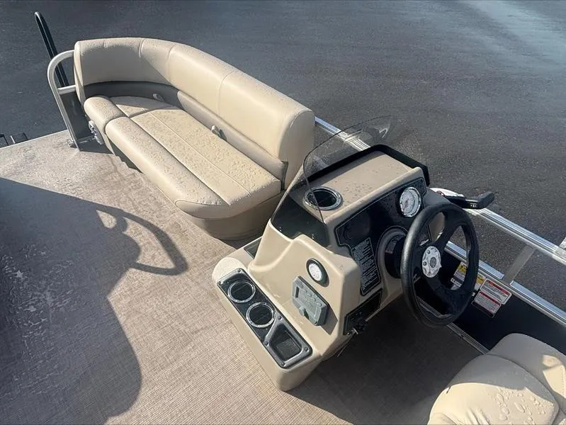 Slide: The Image of 2025 Sun Tracker PB 16 DLX pontoon boat interior with beige seating and steering console. - 3