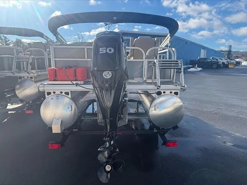 Slide: The Image of 2025 Sun Tracker PB 16 DLX pontoon boat with 50 HP engine, parked outdoors. - 7