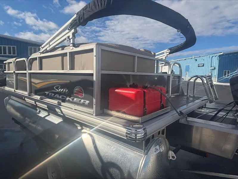 Slide: The Image of 2025 Sun Tracker PB 16 DLX pontoon boat with canopy, docked under a clear blue sky. - 8