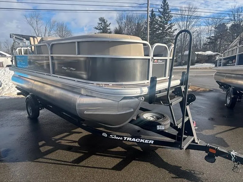 Slide: The Image of 2025 Sun Tracker PB 16 DLX pontoon boat on trailer, parked outdoors. - 9