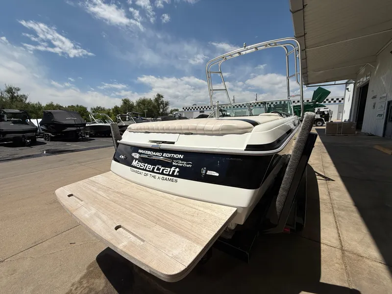 Slide: The Image of 2000 MasterCraft XStar boat with swim platform, parked outdoors under a clear sky. - 6