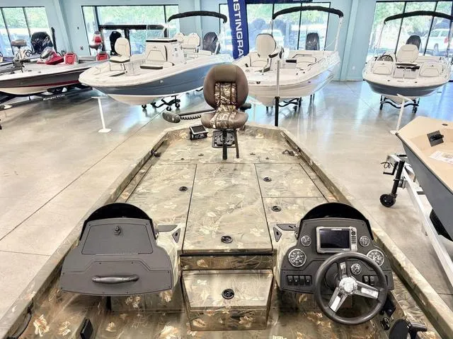 Slide: The Image of 2017 Ranger RT198P fishing boat interior with camouflage design, steering console, and seating in showroom. - 4