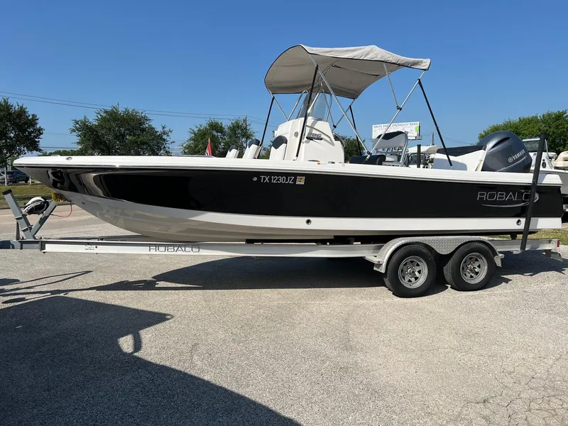 Slide: The Image of 2021 Robalo 226 Cayman boat on trailer, black and white design, parked outdoors. - 1