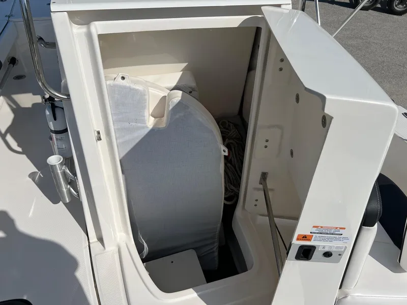 Slide: The Image of 2021 Robalo 226 Cayman boat storage compartment with open hatch and visible equipment. - 17