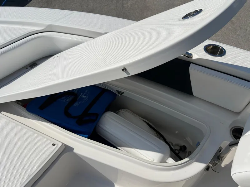 Slide: The Image of 2021 Robalo 226 Cayman boat storage compartment with open lid, revealing life jackets inside. - 21