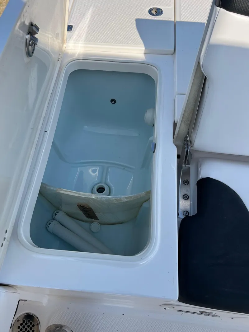 Slide: The Image of 2021 Robalo 226 Cayman boat storage compartment with open lid, showcasing interior space. - 7