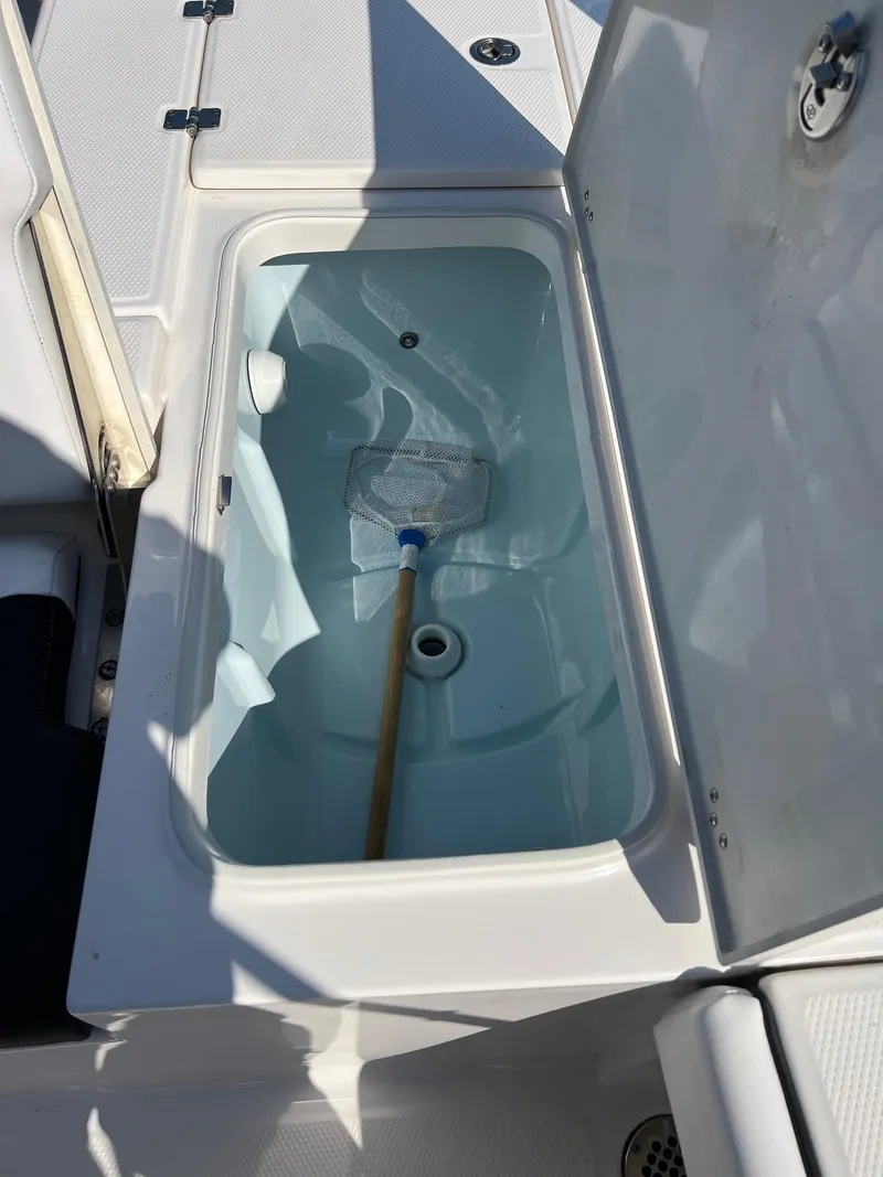 Slide: The Image of 2021 Robalo 226 Cayman boat livewell with open lid and net inside. - 8