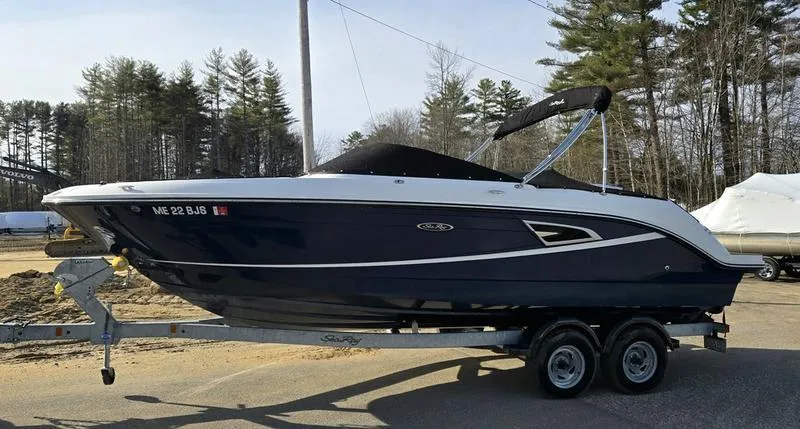 Slide: The Image of 2019 Sea Ray SLX 230 boat on trailer, parked outdoors with trees in background. - 6