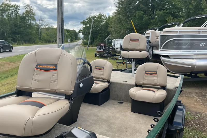 Slide: The Image of 2025 Tracker BT CLASSIC SE boat with beige seats, parked near a road and trees. - 16