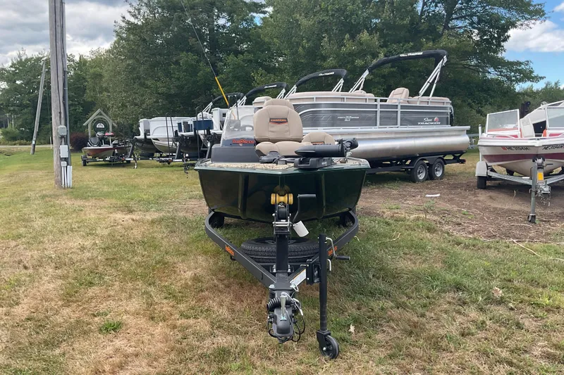 Slide: The Image of 2025 Tracker BT CLASSIC SE boat on trailer, surrounded by other boats, grassy area. - 7