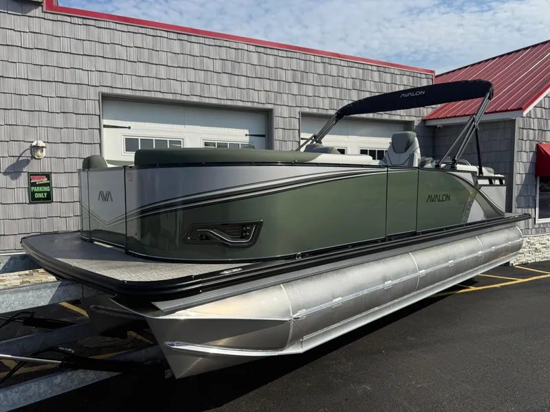 Slide: The Image of 2025 Avalon 2385 LSZ Quad Lounger Tri Toon boat parked outside a building. - 1