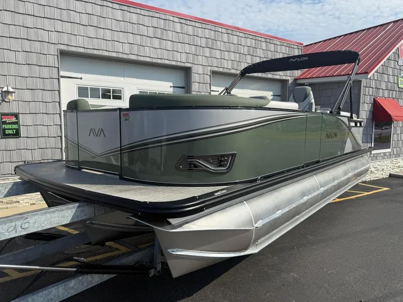 Slide: The Image of 2025 Avalon 2385 LSZ Quad Lounger Tri Toon boat, high performance, parked outside a building. - 2