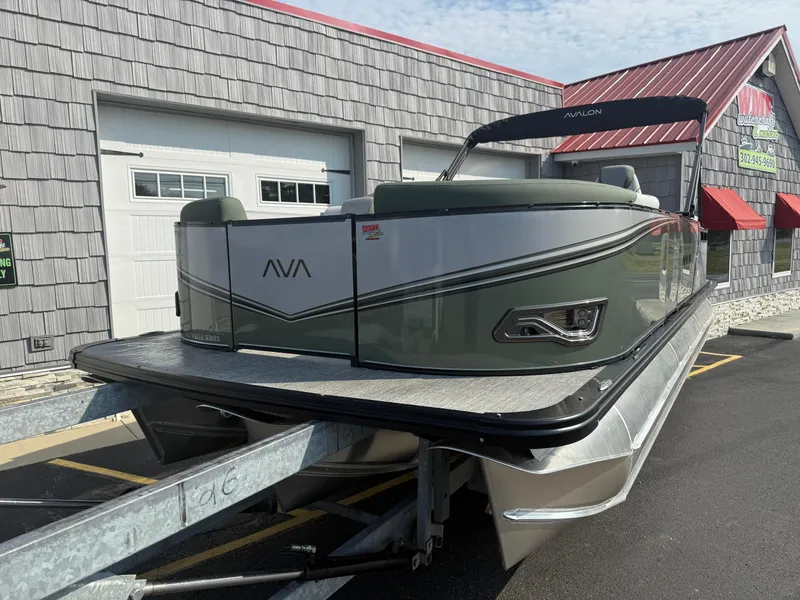 Slide: The Image of 2025 Avalon 2385 LSZ Quad Lounger Tri Toon boat on trailer, parked outside building. - 3