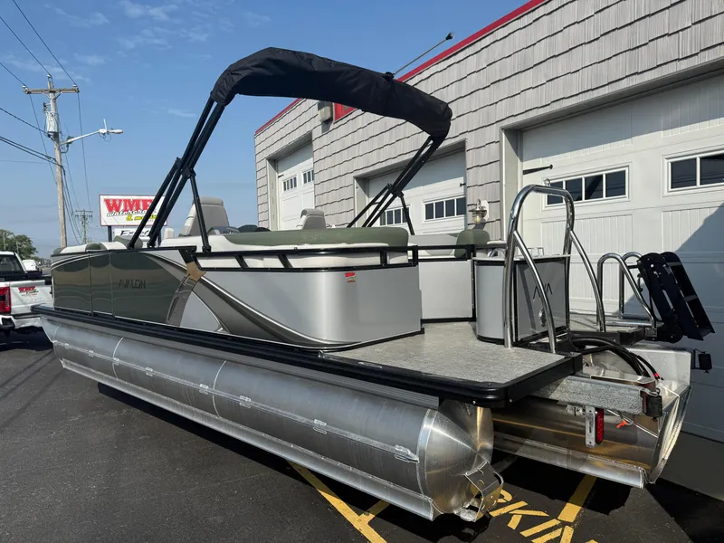 Slide: The Image of 2025 Avalon 2385 LSZ Quad Lounger Tri Toon boat parked outside a garage. - 4