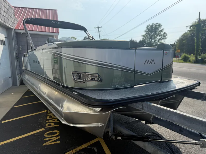 Slide: The Image of 2025 Avalon 2385 LSZ Quad Lounger Tri Toon boat on trailer, parked outside. - 7