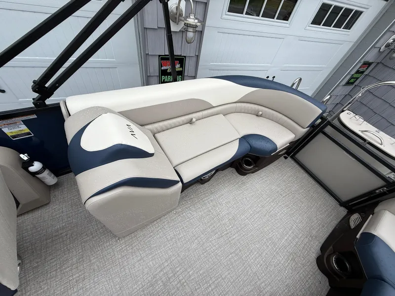 Slide: The Image of 2025 Avalon 2385 LSZ Quad Lounger Tri Toon boat at dealership, blue and white design. - 18