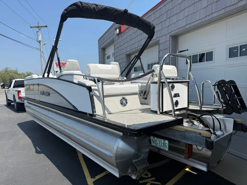 Slide: The Image of 2025 Avalon 2385 Catalina Quad Lounger Tri Toon boat parked near a garage. - 6