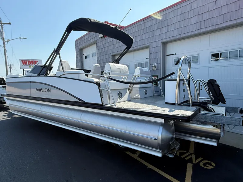 Slide: The Image of 2025 Avalon Catalina Quad Lounger Shift Windshield pontoon boat parked outside a garage. - 6